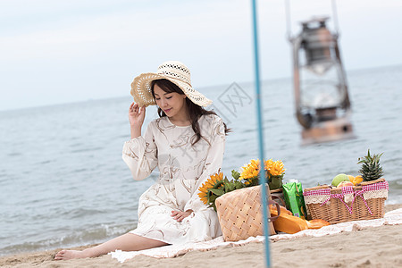 快乐的青年女人坐在沙滩上图片