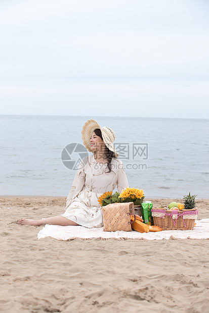 快乐的青年女人坐在沙滩上图片