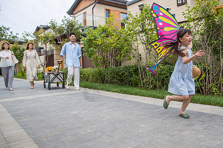家人玩耍拿着风筝的小女孩和家人在户外玩耍背景