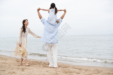 背着女儿的父亲幸福的一家三口在海边玩耍背景