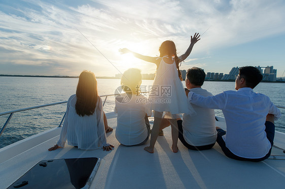 夕阳下坐在游艇上的快乐一家人图片