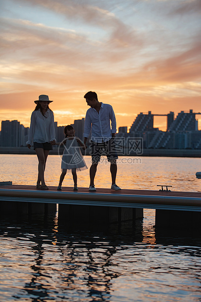 夕阳下一家三口在海边玩耍图片