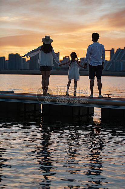 夕阳下一家三口在海边玩耍图片