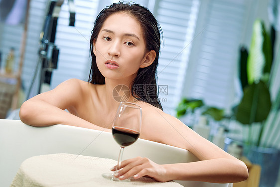 浴缸内漂亮的年轻女人和红酒图片