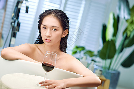 浴缸内漂亮的年轻女人和红酒图片