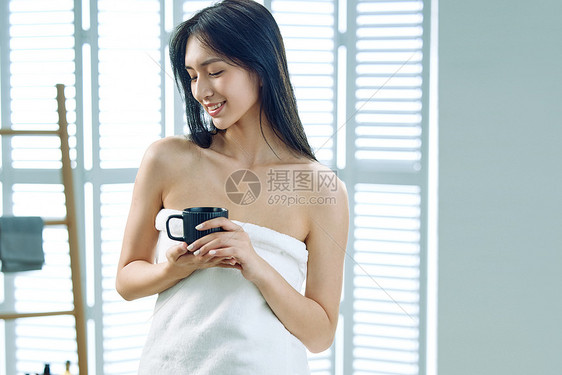 裹着浴巾的青年女人端着杯子图片