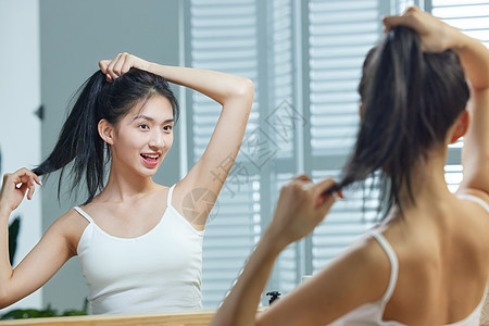 漂亮的年轻女人照着镜子梳头发图片