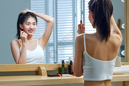 漂亮的年轻女人照着镜子梳头发图片