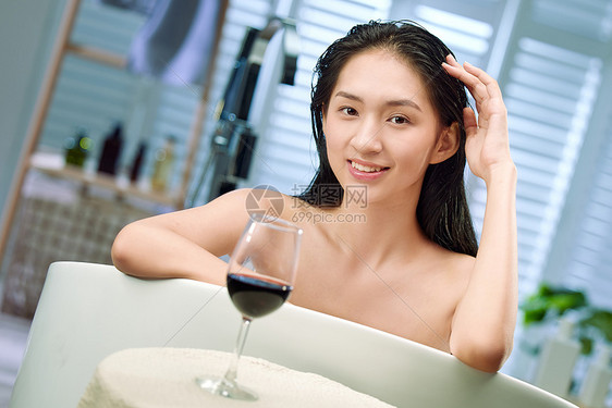 浴缸内漂亮的年轻女人和红酒图片