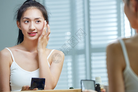 漂亮的年轻女人照着镜子化妆图片
