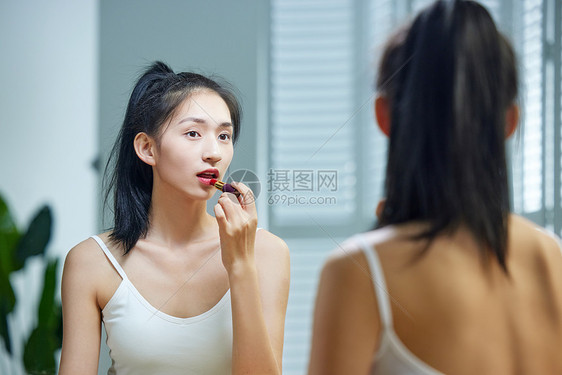 漂亮的年轻女人照着镜子涂口红图片