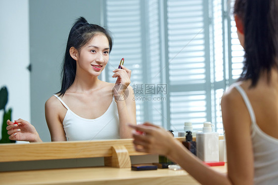漂亮的年轻女人照着镜子涂口红图片