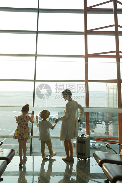 年轻妈妈和孩子在机场候机厅往外看图片