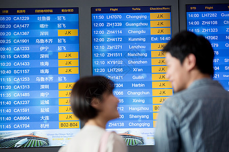 青年情侣在机场候机厅看航班表背景图片