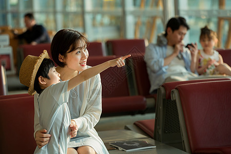 年轻妈妈和儿子坐在机场候机厅图片