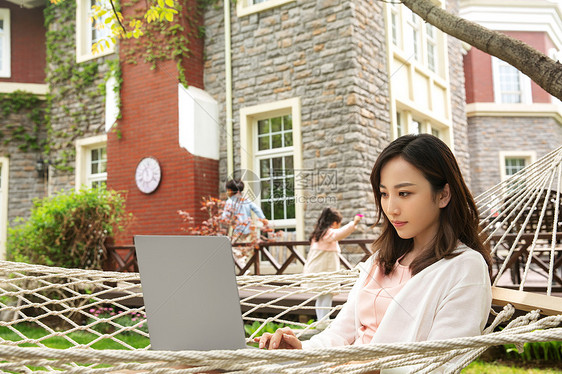 青年女人在院子里用笔记本电脑图片