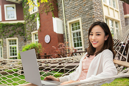 青年女人在院子里用笔记本电脑图片