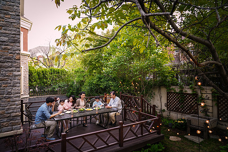 喝菊花酒女孩快乐大家庭在庭院里用餐背景