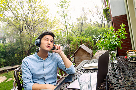 花园办公青年男人在院子里听音乐背景