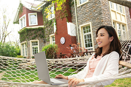 青年女人在院子里用笔记本电脑图片
