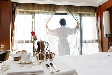 年轻女人在酒店房间里拉开窗帘图片