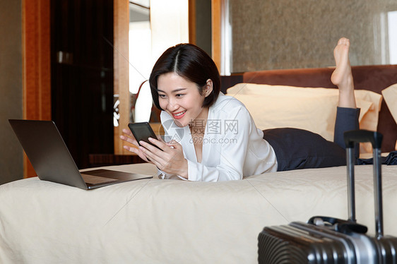 年轻女人趴在床上看手机图片
