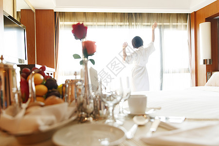 早晨开窗年轻女人在酒店房间里拉开窗帘背景