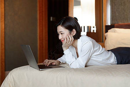 年轻女人趴在床上用电脑图片