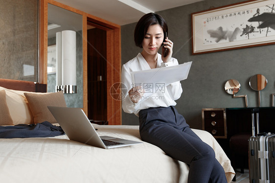 年轻女人坐在床上打电话图片