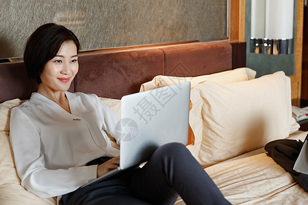 年轻女人坐在床上用电脑图片