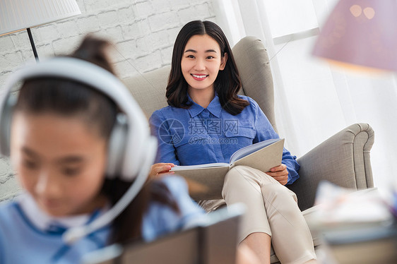 青年女人在家陪伴孩子学习图片