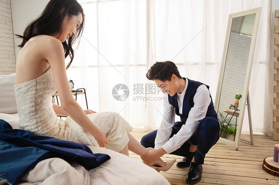 年轻的丈夫蹲下给妻子穿鞋图片