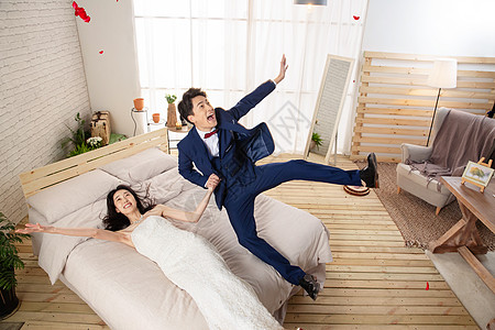 兴奋的新婚夫妇倒在床上图片