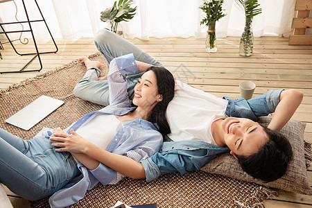 快乐情侣躺在地毯上享受午后时光图片
