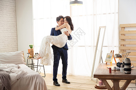 卧室里幸福的丈夫把妻子抱起来图片
