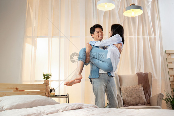 卧室里年轻丈夫把妻子抱了起来图片