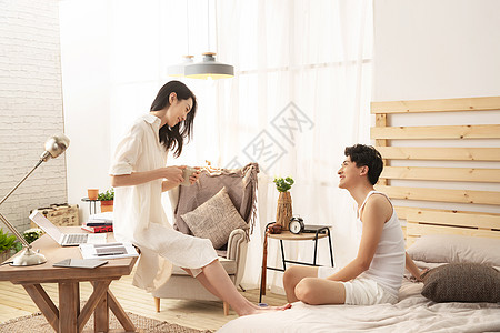 卧室里年轻的妻子坐在桌子上和丈夫聊天图片