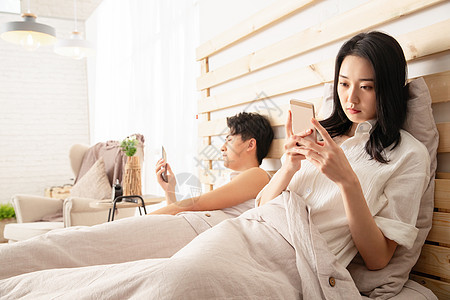 年轻情侣在床上使用手机图片