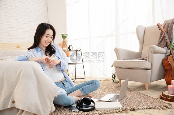 快乐的女青年坐在地毯上图片