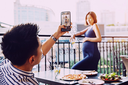 青年夫妇在餐厅用手机照相图片