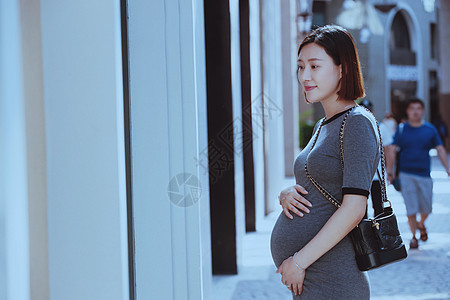 孕妇站在商店橱窗前图片