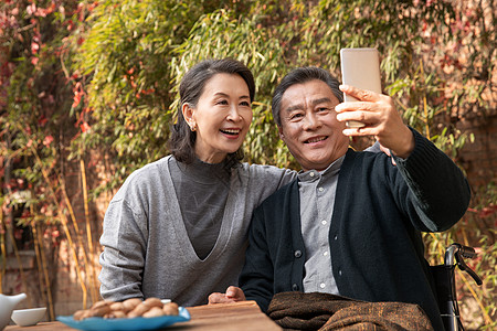 户外庭院老年夫妇在庭院使用手机自拍背景