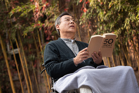 户外老年男人坐在轮椅上看书图片