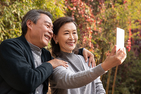 老年夫妇在庭院使用手机自拍图片