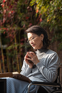 户外老年女人坐在轮椅上看书图片