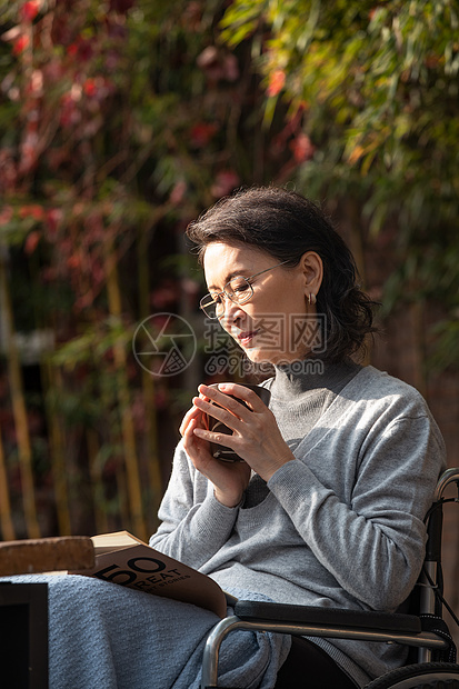 户外老年女人坐在轮椅上看书图片