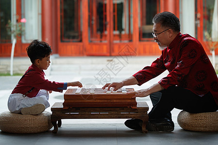 小男孩侧面祖孙俩在庭院里下象棋背景