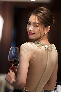 红葡萄酒漂亮的青年女人拿着高脚杯背景
