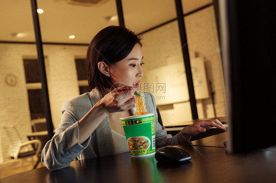 在办公室加班吃方便面的青年女人图片