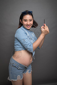 穿着时尚的孕妇拿着手机图片
